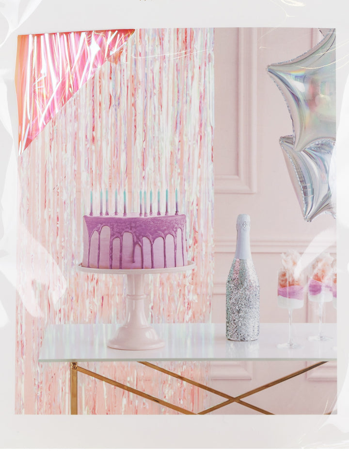 Rosafärgat glitterdraperi dekorerat bakom ett kalasbord med tårta, glas och ballonger