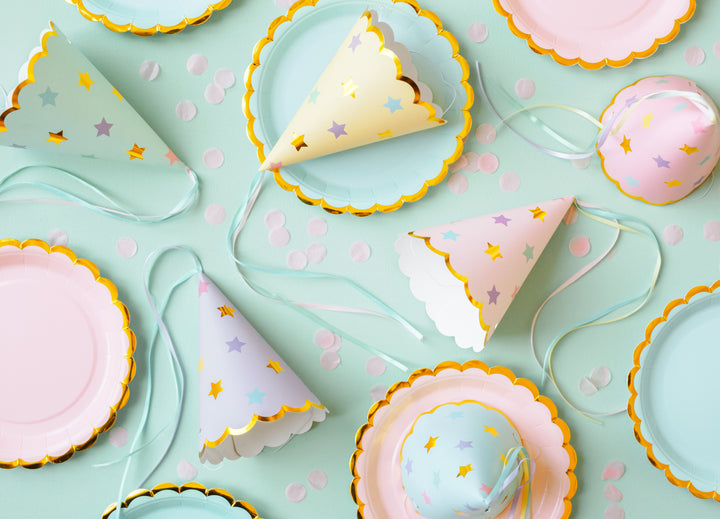 Inspirationsbild med dukningstillbehör och partyhattar i pastellfärg och guldkant till barnkalas och fest