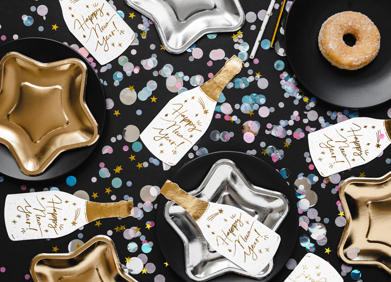 Pappersservett champagneflaska i färgerna vitt och guld. Dukat till nyårsfirande och fest.